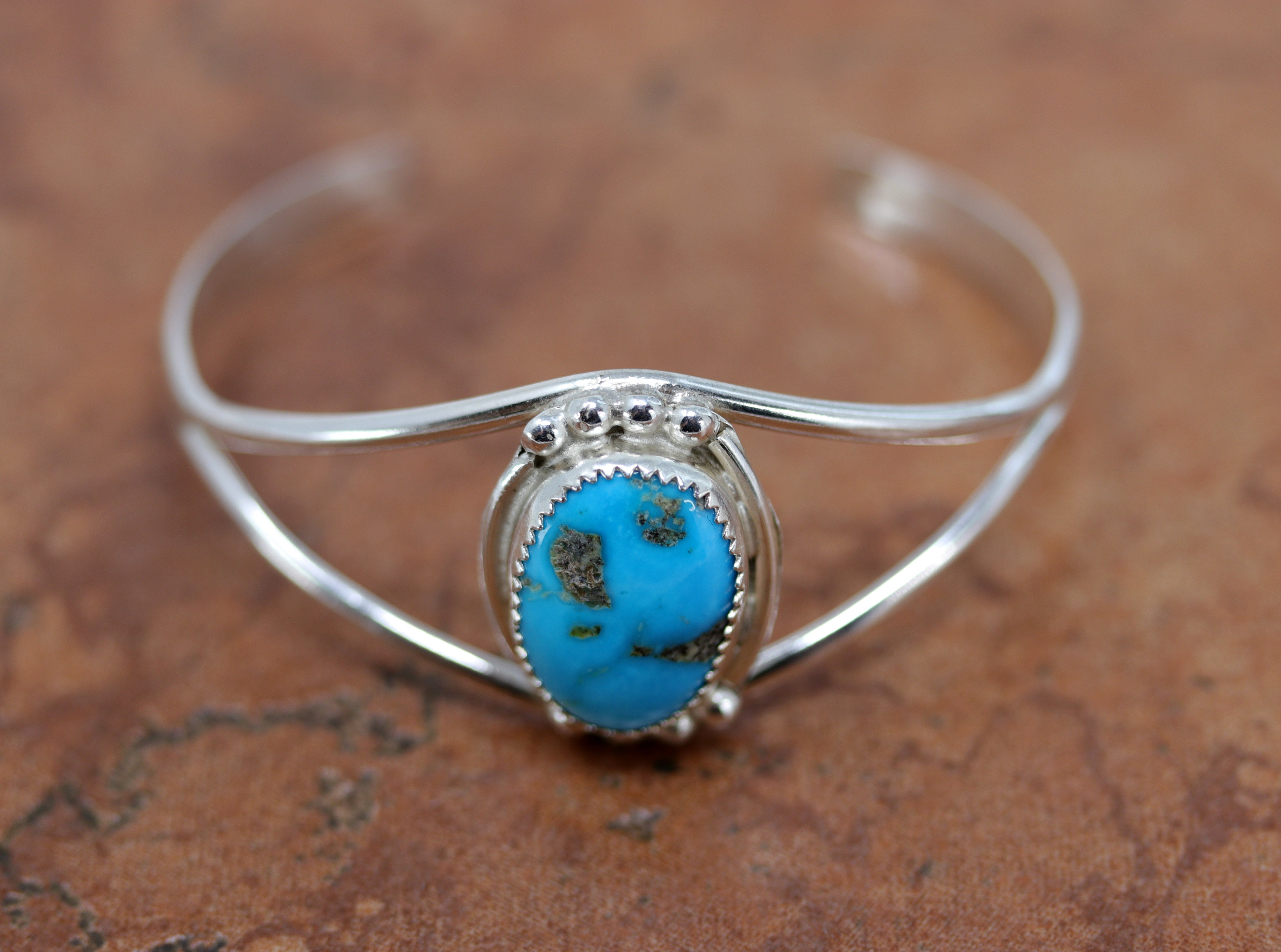 Silver cuff bracelet with a large oval shaped turquoise stone  in  the center