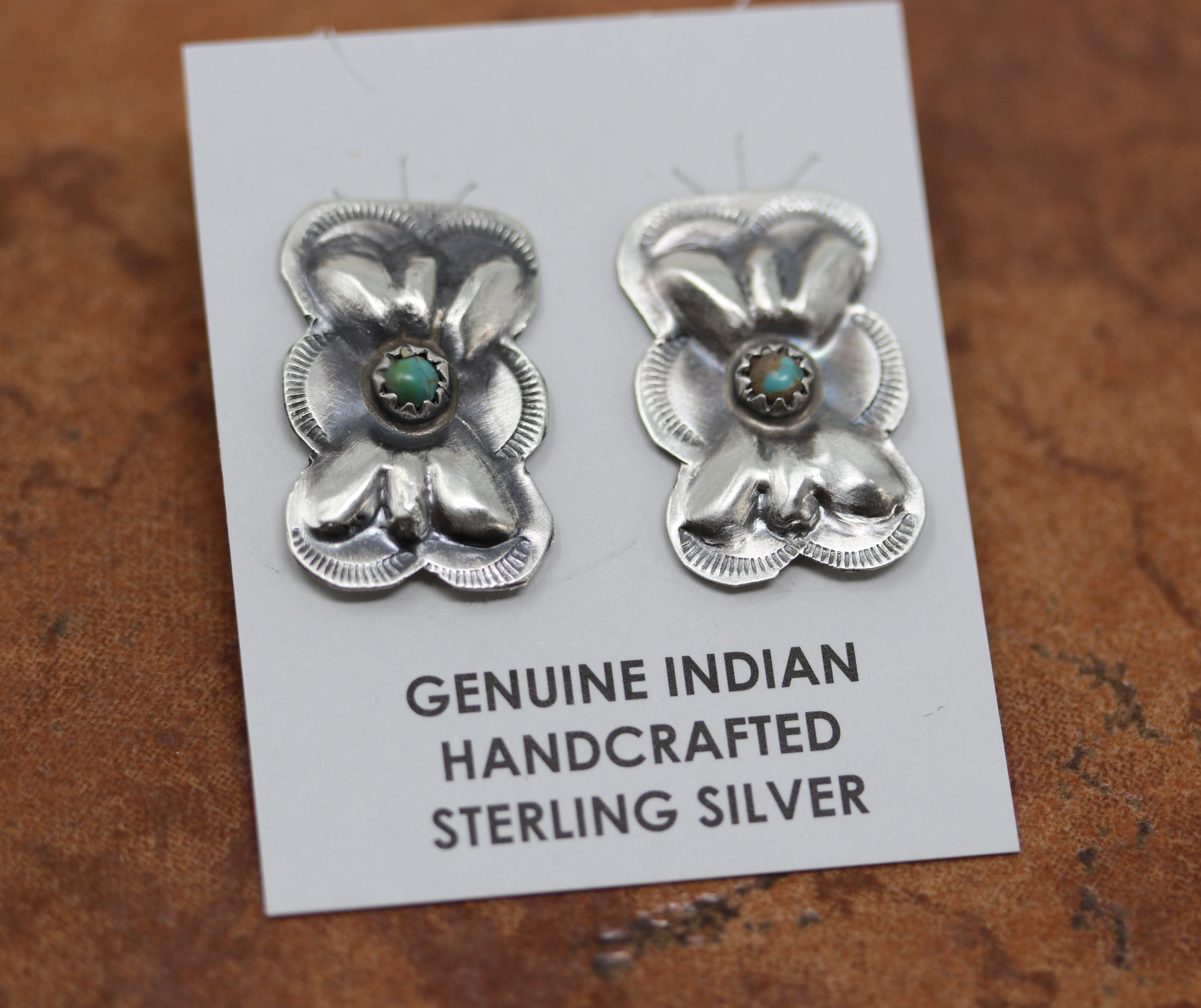 Silver butterfly earrings with circular turquoise gemstones in the center