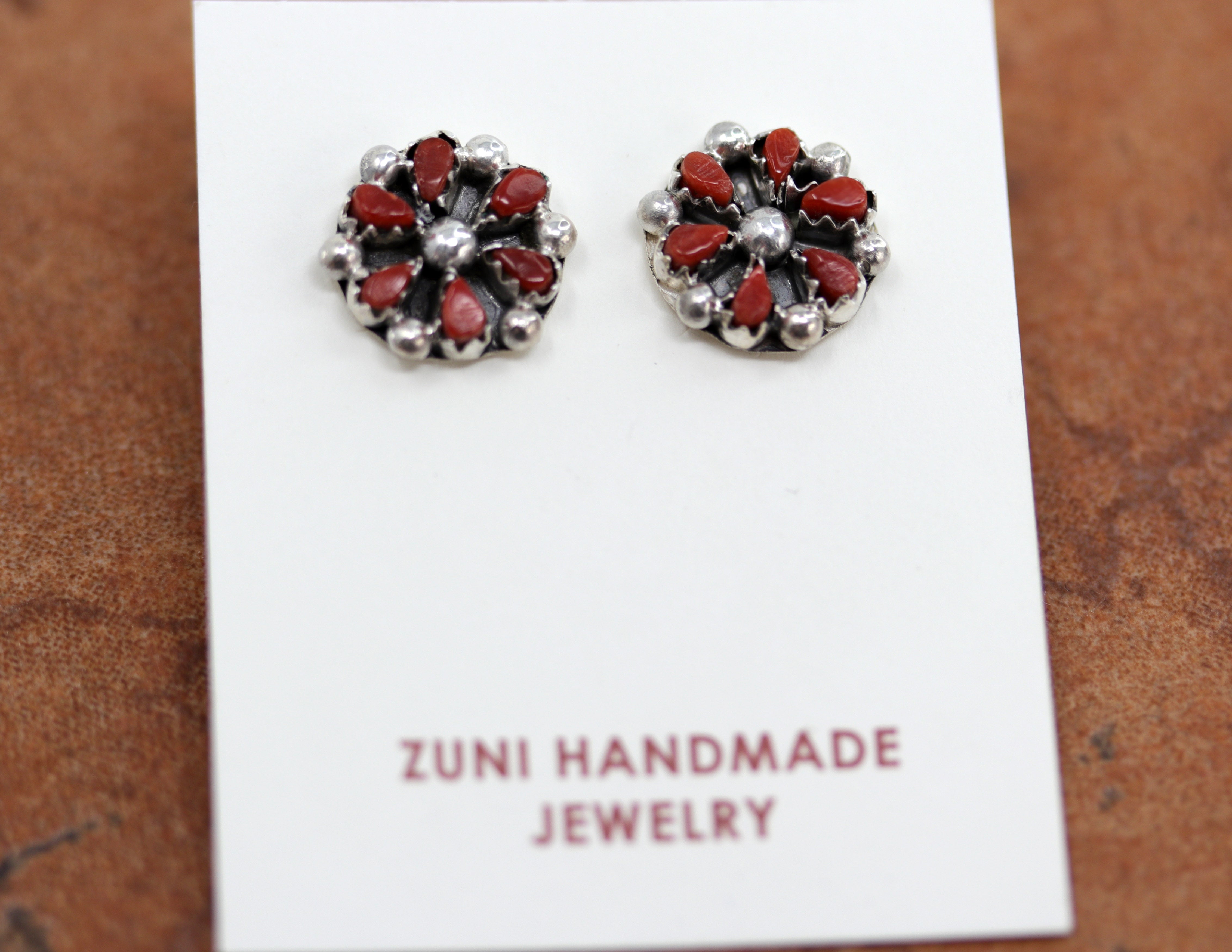 Circular cluster earrings with six red coral stones in them
