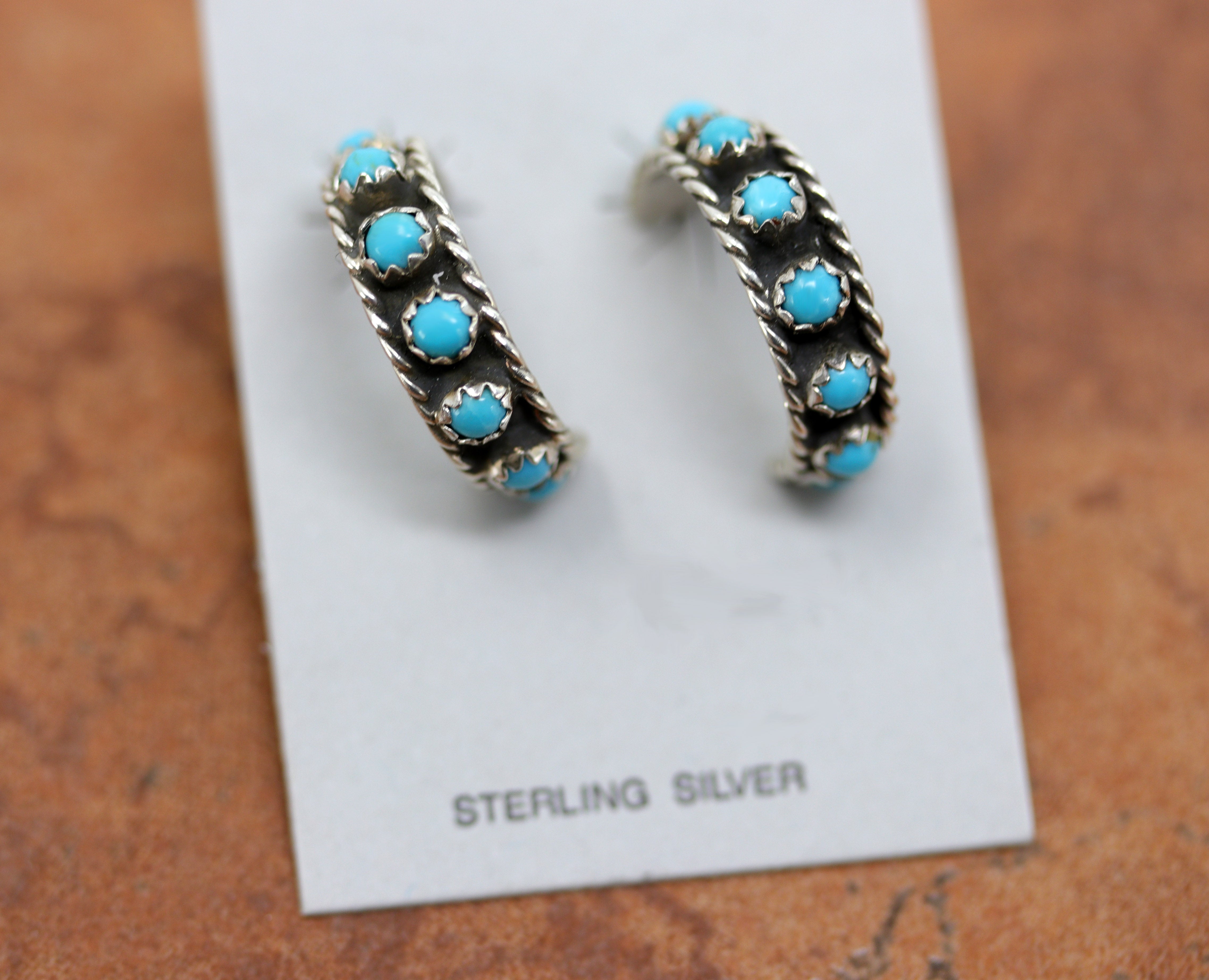 Silver hoop earrings with small circular turquoise stones going around it